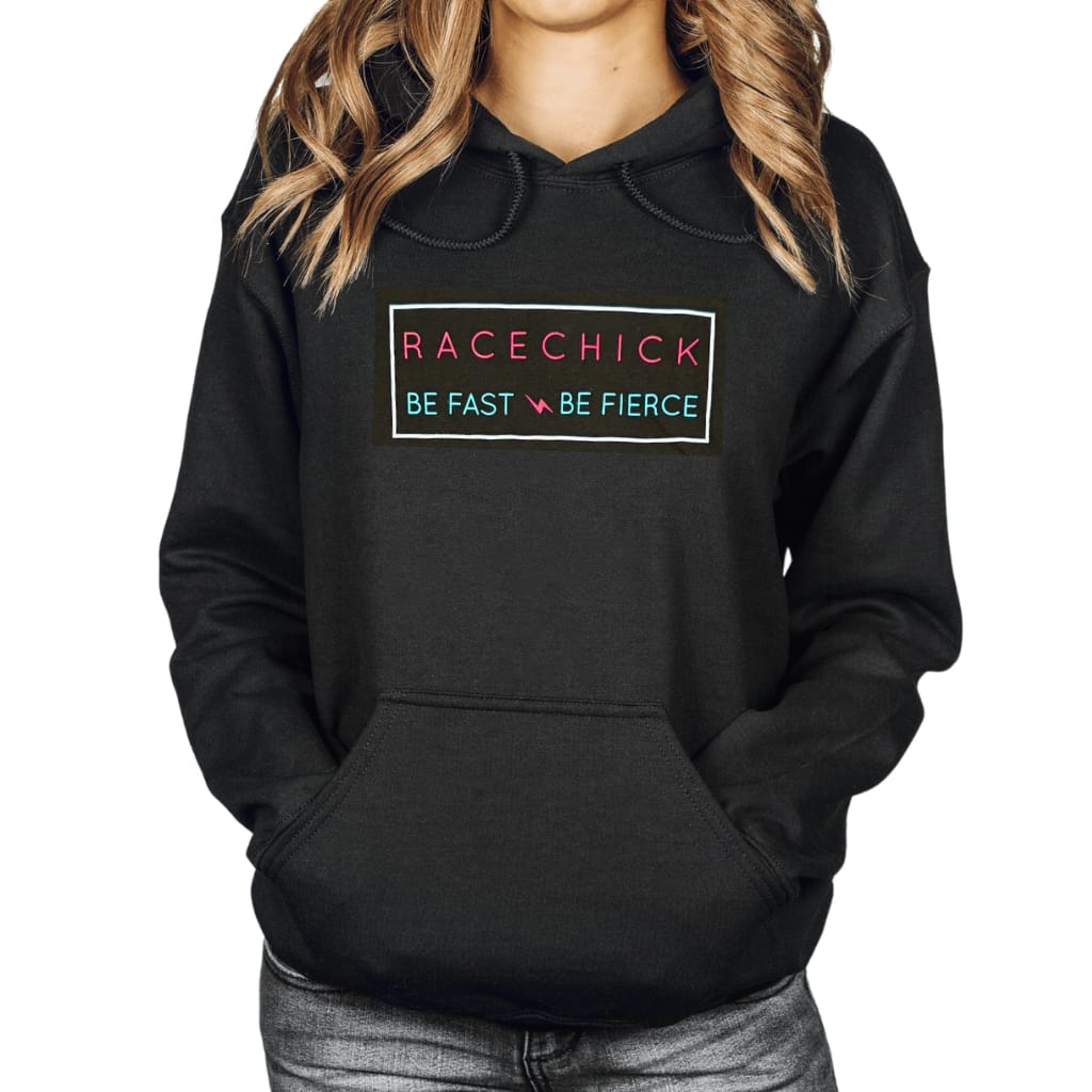 A woman wearing a black pullover hoodie with a graphic on the chest that reads 'RACECHICK BE FAST BE FIERCE' in pink and teal text inside a thin rectangular border.